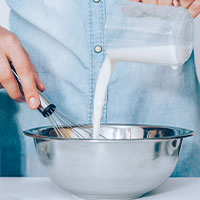 mano che versa latte in una ciotola