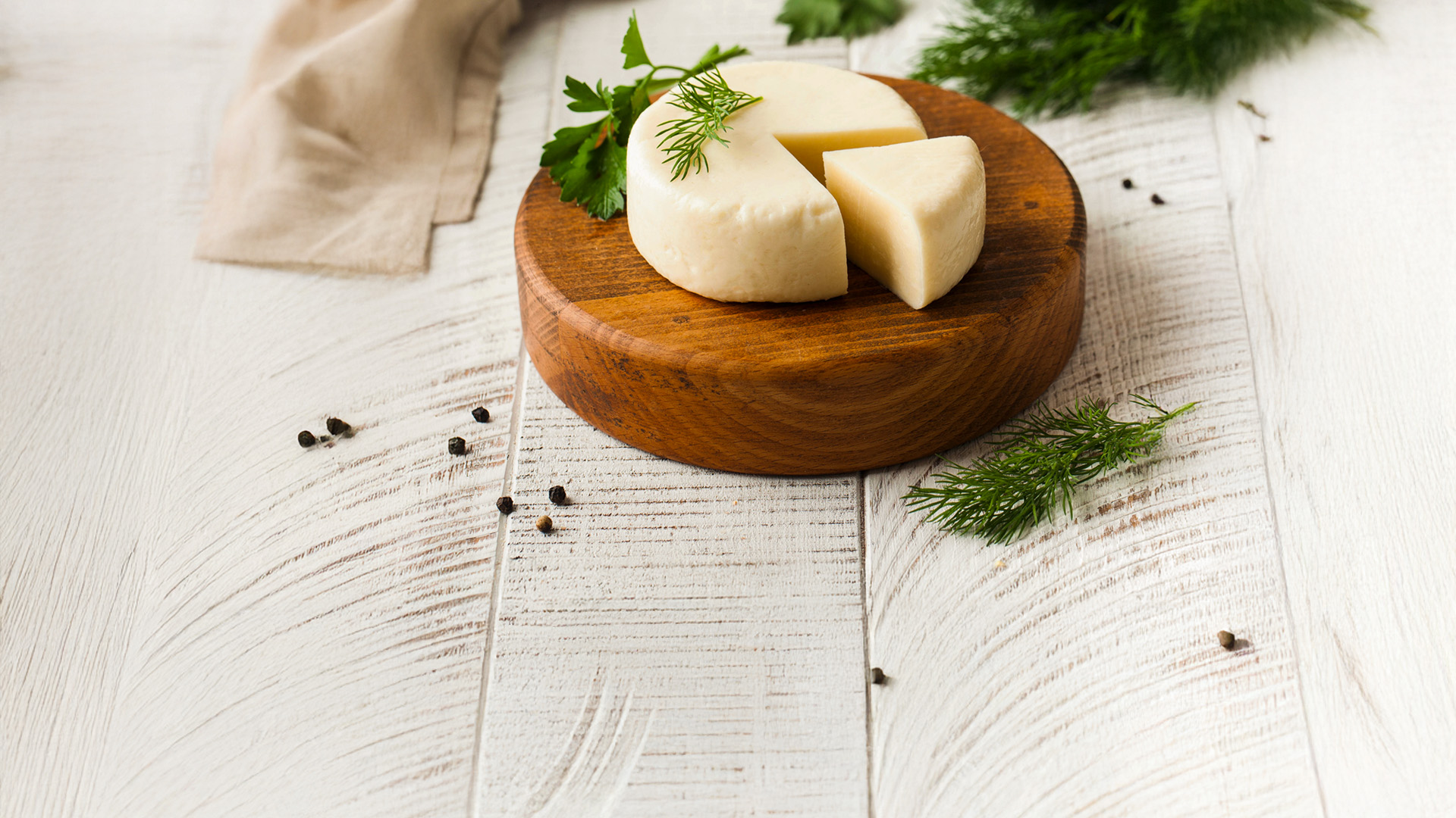 formaggio morbido, forma intera con fetta tagliata su tagliere tondo