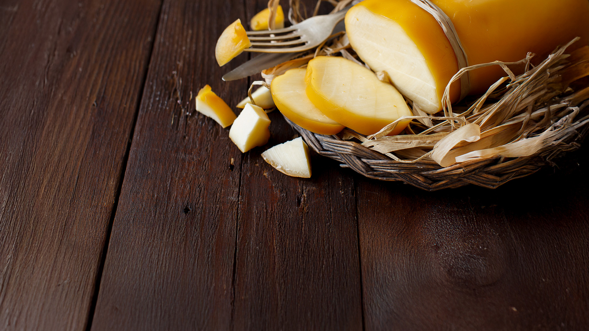 provola affumicata, fette, pezzetti e forma su legno scuro